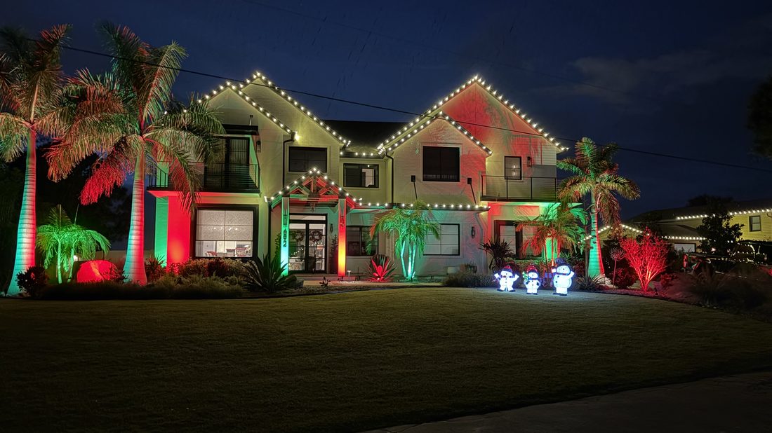 Two-storey home with red and green lighting and lit snowmen